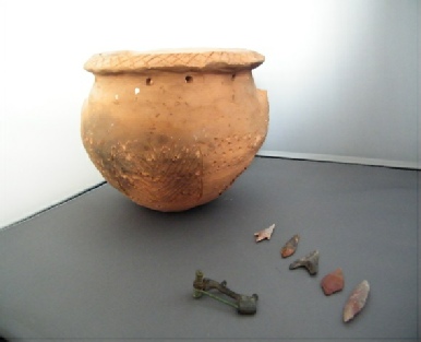 A large achient pot along with stoneage tools